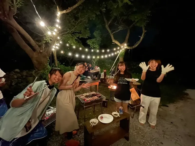 Groupe de personnes souriantes autour d'un barbecue en soirée festive