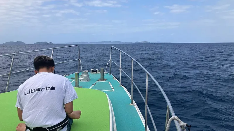Homme regardant l'horizon depuis la proue d'un bateau de plongée