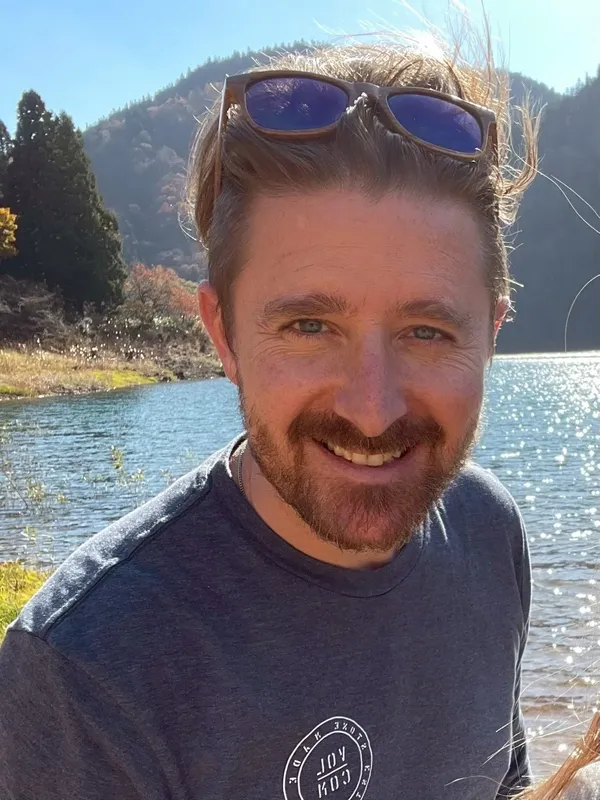 Portrait d'un homme souriant avec des lunettes de soleil au bord de l'eau