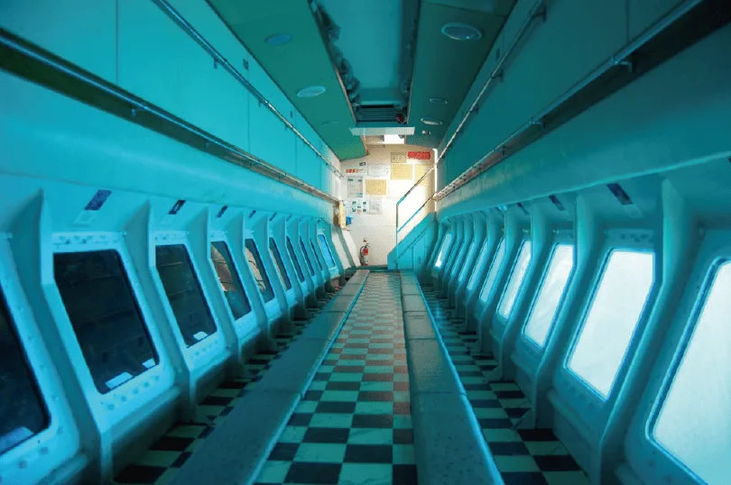 Couloir intérieur d'une épave avec hublots et sol damier