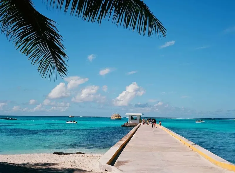 Ponton menant à un quai avec des personnes et des bateaux turquoise