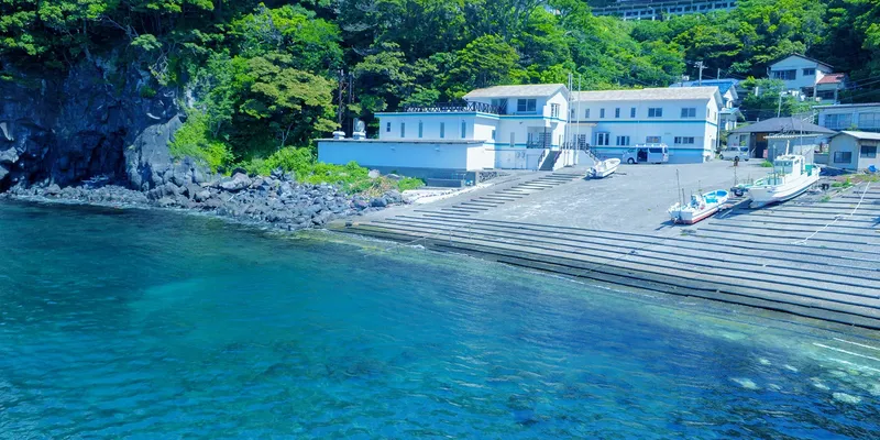 Centre de plongée avec bâtiments blancs, bateaux amarrés et accès à la mer