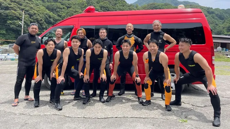 Groupe de personnes souriantes posant devant un van rouge