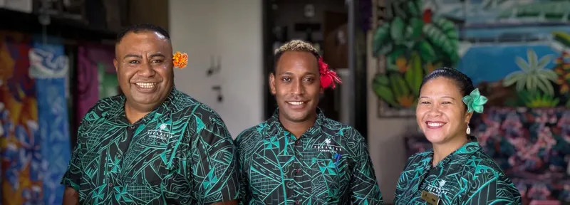 Trois personnes souriantes, portant des chemises à motifs tropicaux