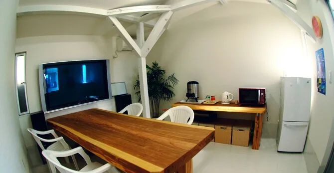 Salle de pause avec table, chaises, cafetière et réfrigérateur blanc