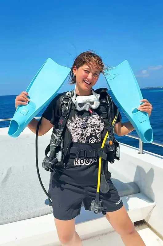 Plongeuse souriante tenant son matériel sur le pont d'un bateau