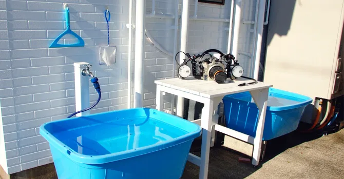 Équipement de plongée sur une table, bacs de rincage bleus et mur blanc