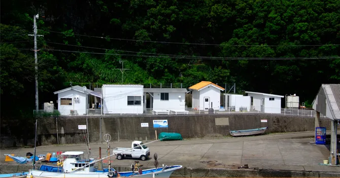 Bâtiments blancs d'un centre de plongée, bateaux amarrés et pick-up