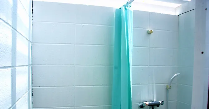 Douche intérieure carrelée avec rideau turquoise et robinetterie simple