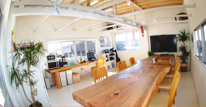 Grande salle lumineuse avec table en bois, ordinateurs et plantes vertes