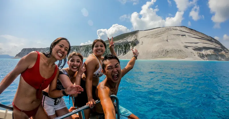 Groupe de personnes souriantes sur un bateau en mer, paysage côtier