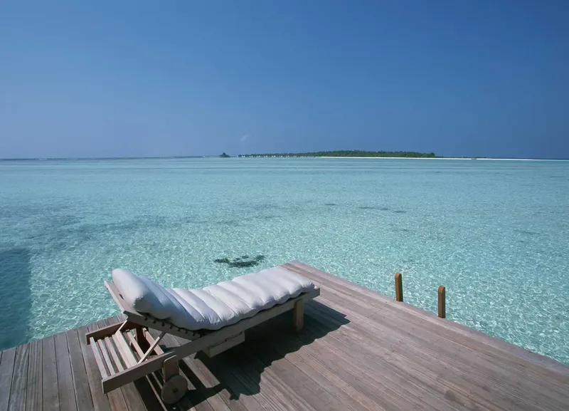 Transat blanc sur ponton en bois, mer turquoise et ciel bleu