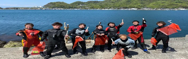 Groupe de plongeurs souriants posant avec des objets trouvés en plongée