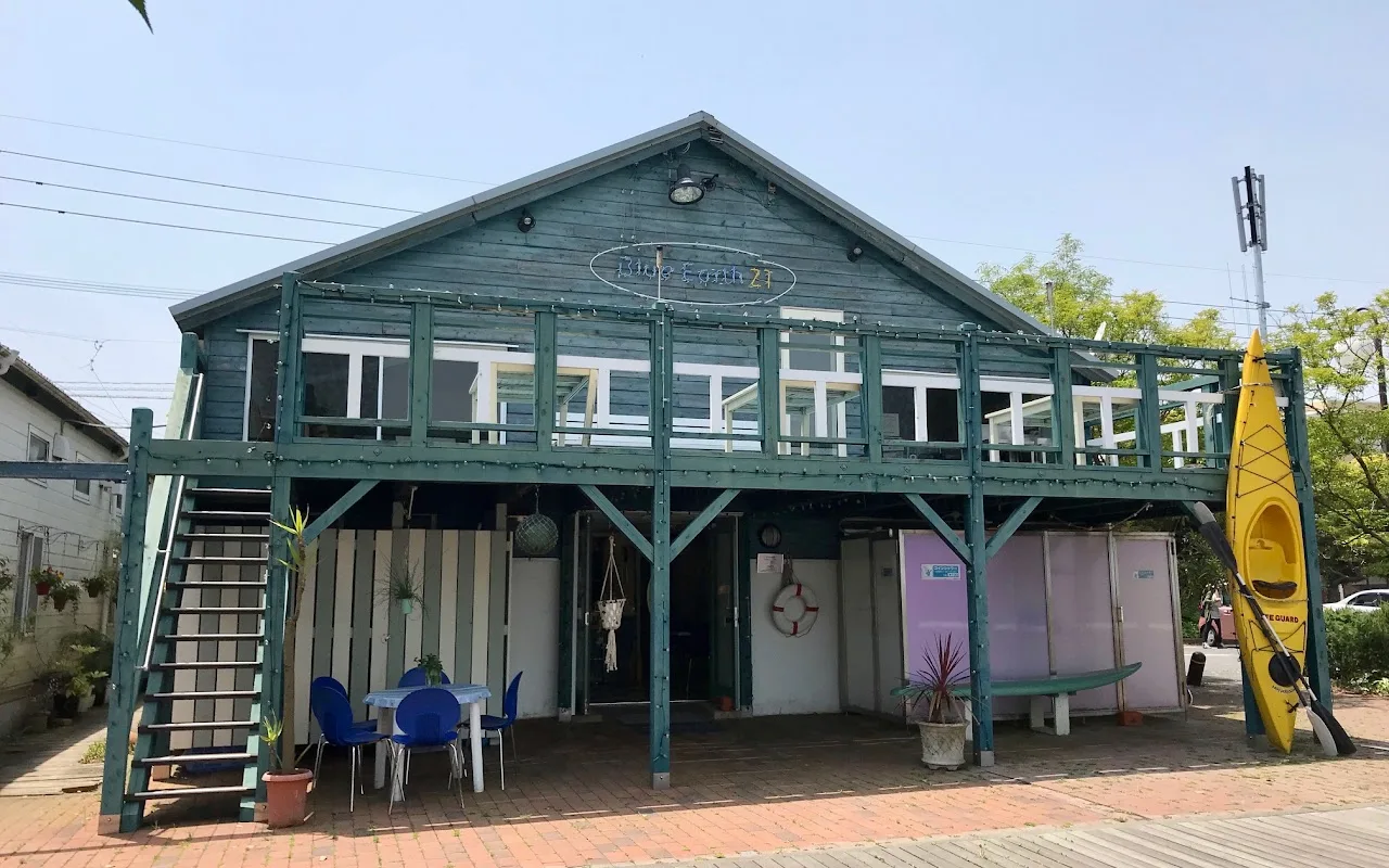 Façade d'un bâtiment vert avec balcon, tables et un kayak jaune