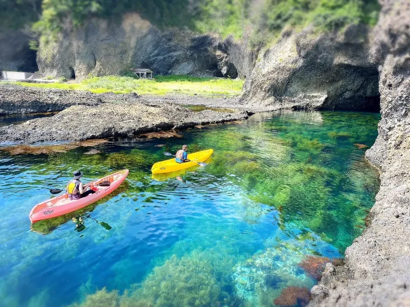 Deux kayaks naviguent sur une eau turquoise claire et calme