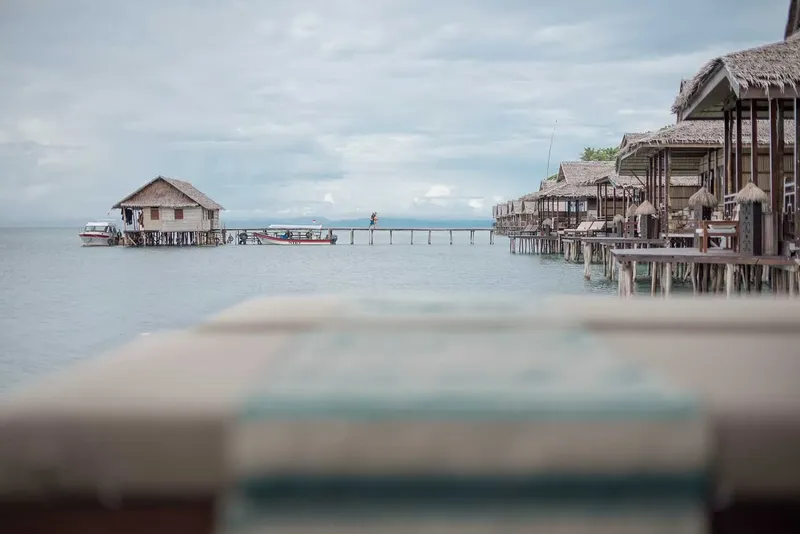 Cabanes sur pilotis au bord de l'eau avec bateaux et personnes