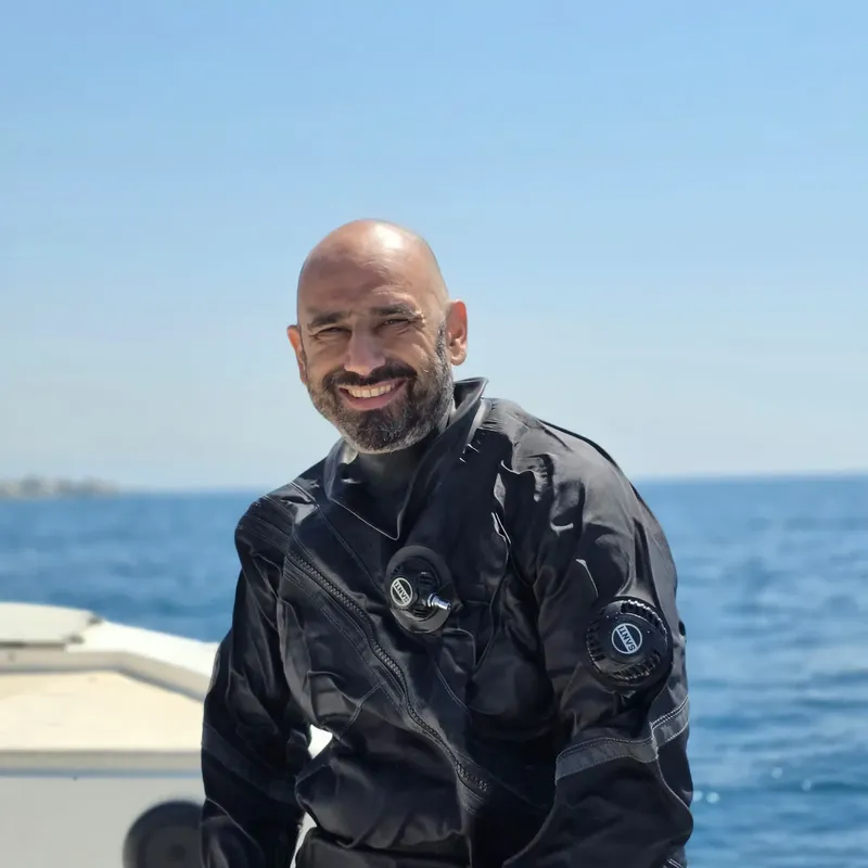 Plongeur souriant en combinaison, équipé, sur un bateau en mer