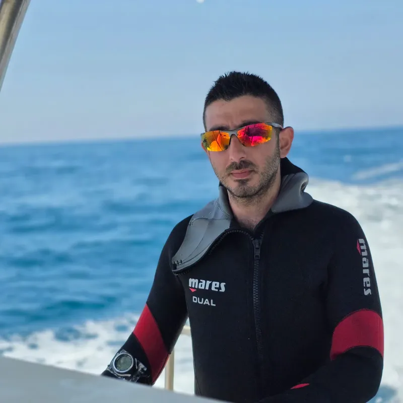 Plongeur en combinaison noire et lunettes de soleil sur un bateau