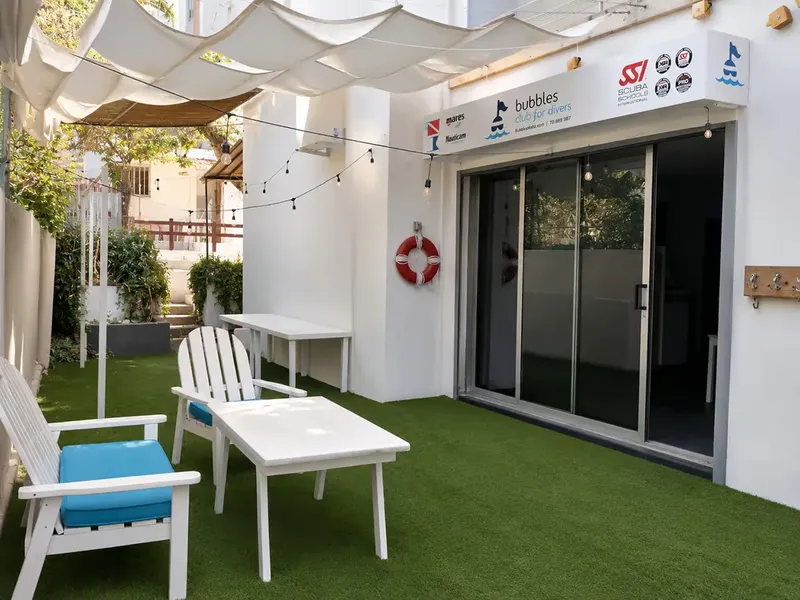 Terrasse avec mobilier blanc devant l'entrée d'un centre de plongée