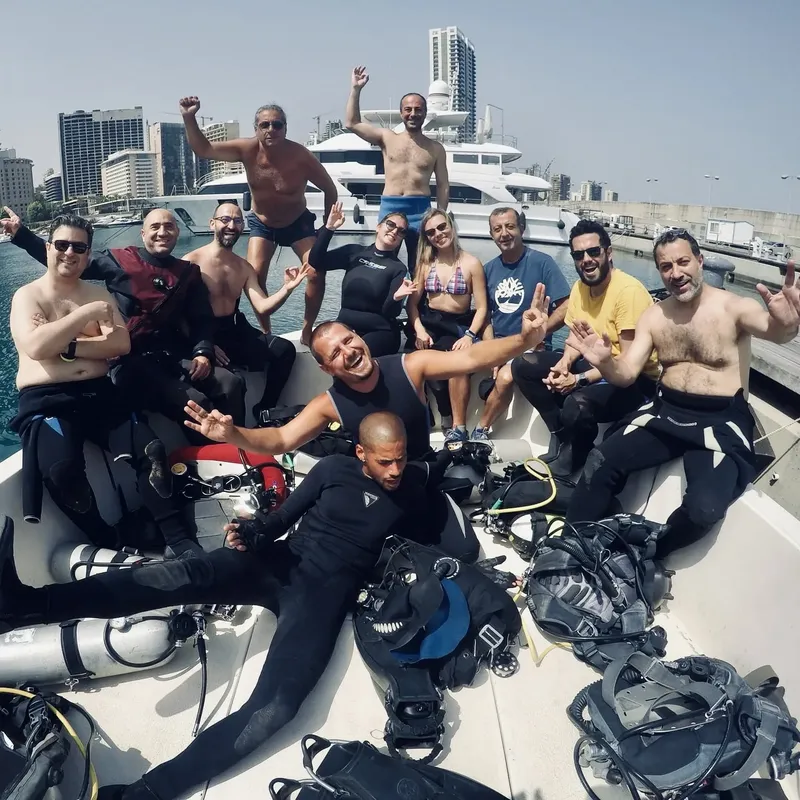 Groupe de plongeurs souriants sur un bateau avec équipement complet