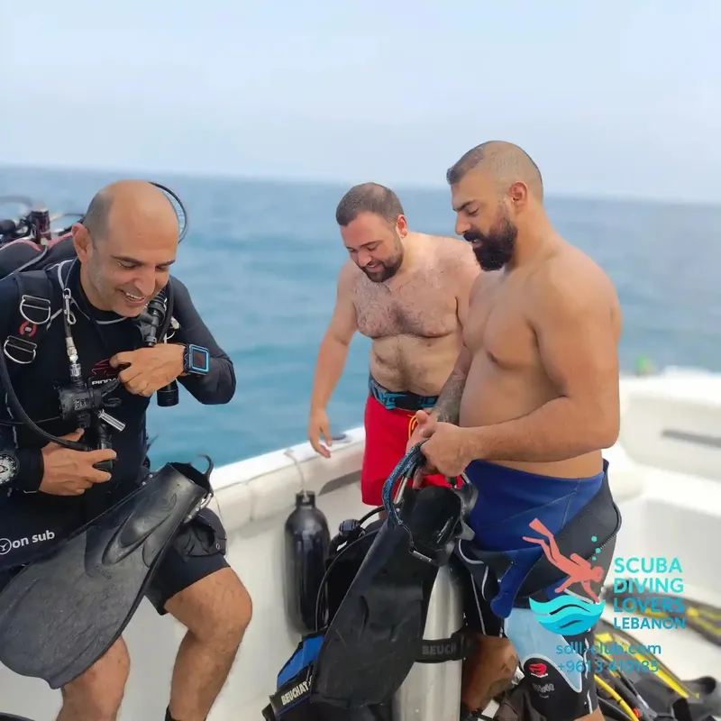 Deux plongeurs sur un bateau, équipés et prêts à plonger en mer