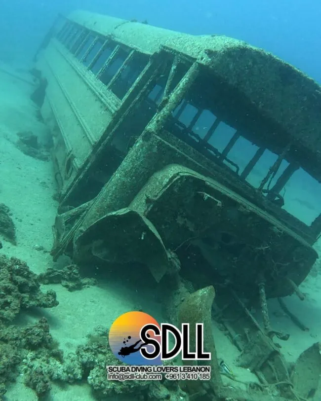 Épave de bus submergée, sable, corail et logo SDLL en bas