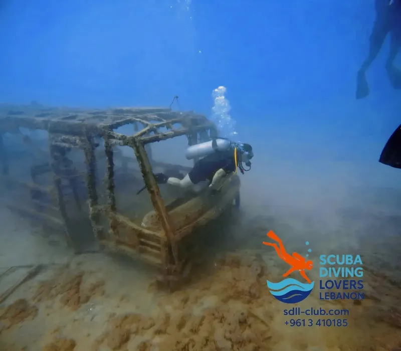 Plongeurs explorant une épave de voiture sous l'eau sableux