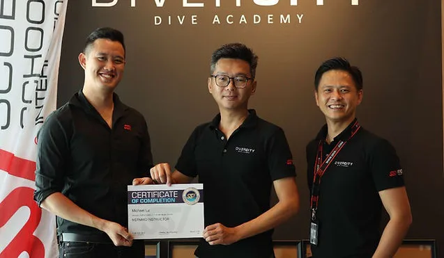Trois hommes souriants posent avec un certificat de formation plongée