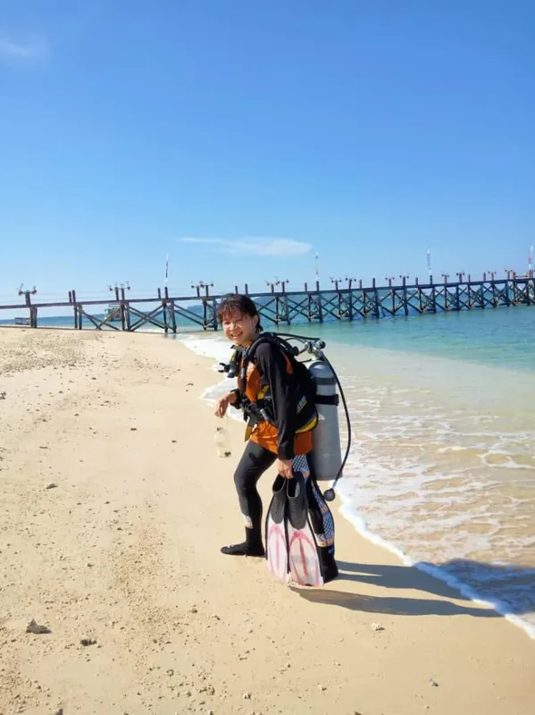 Plongeur équipé sur une plage avec un ponton en arrière-plan
