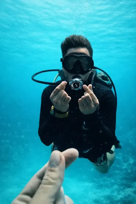 Plongeur souriant faisant un coeur avec ses mains sous l'eau
