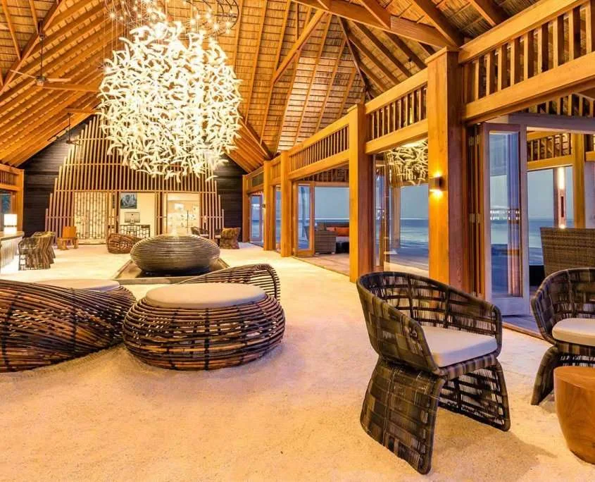 Espace détente intérieur lumineux avec mobilier en bois et vue mer