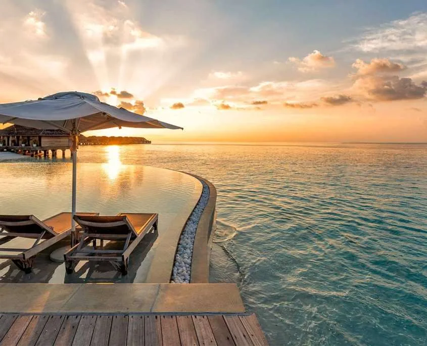 Terrasse en bois avec transats au bord d'une mer turquoise