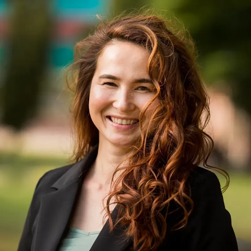 Portrait souriant d'une jeune femme aux cheveux roux et ondulés