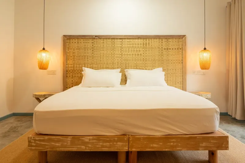 Chambre avec grand lit, tête de lit en bois et éclairage chaleureux