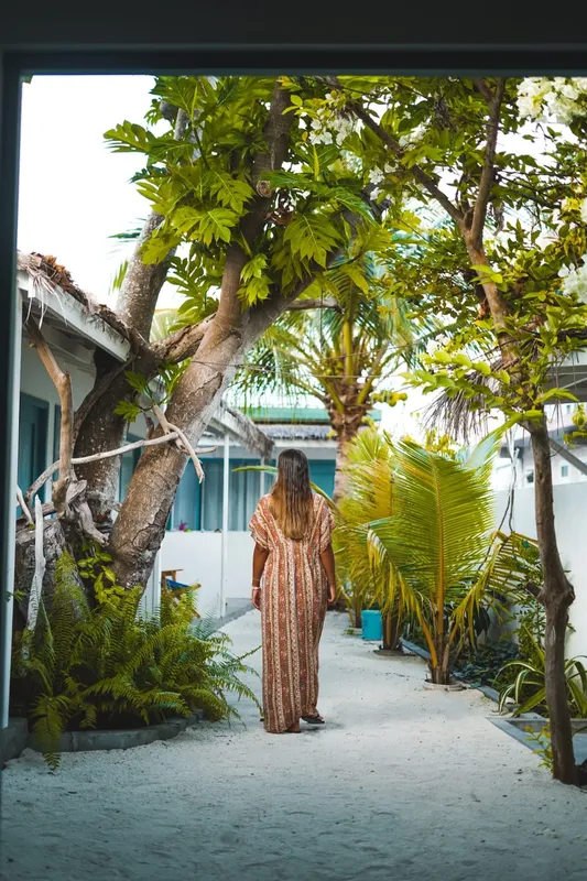 Une femme marche sur un chemin bordé de végétation tropicale