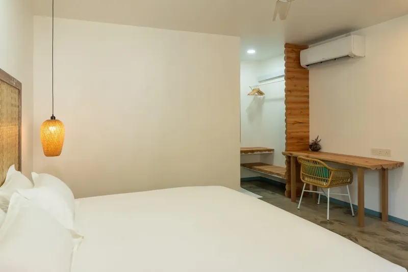 Chambre d'hôtel lumineuse avec lit blanc et bureau en bois naturel