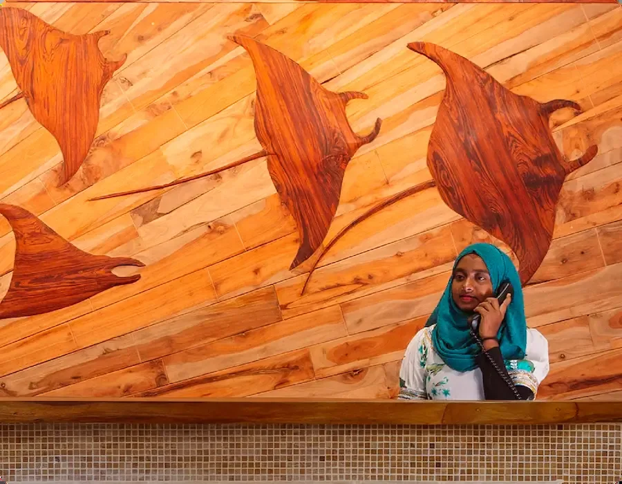 Femme au téléphone devant un mur décoré de raies manta en bois