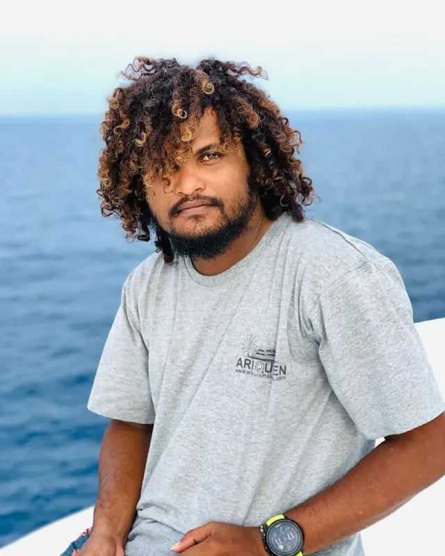 Portrait d'un homme aux cheveux bouclés, regardant la caméra, en extérieur