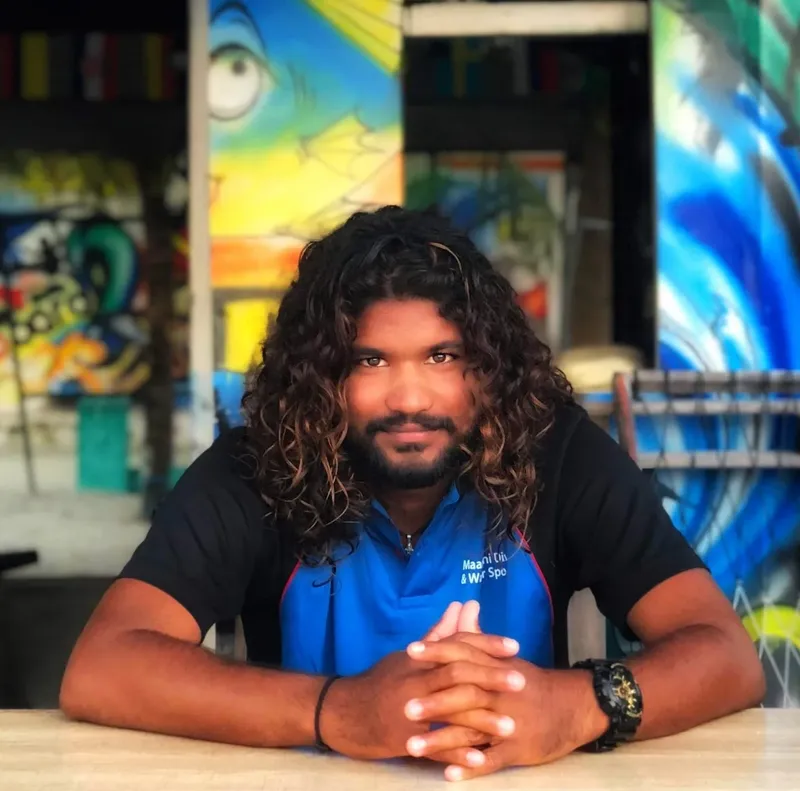 Portrait d'un homme souriant, assis devant un décor coloré et abstrait