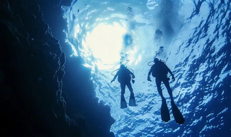 Deux plongeurs explorent une grotte sous-marine, lumière vive au fond