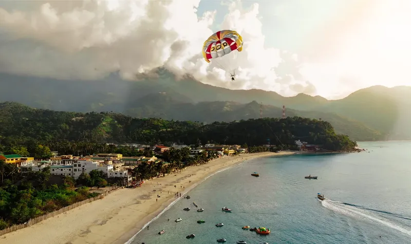 Personne en parachute ascensionnel au-dessus d'une plage et de bateaux