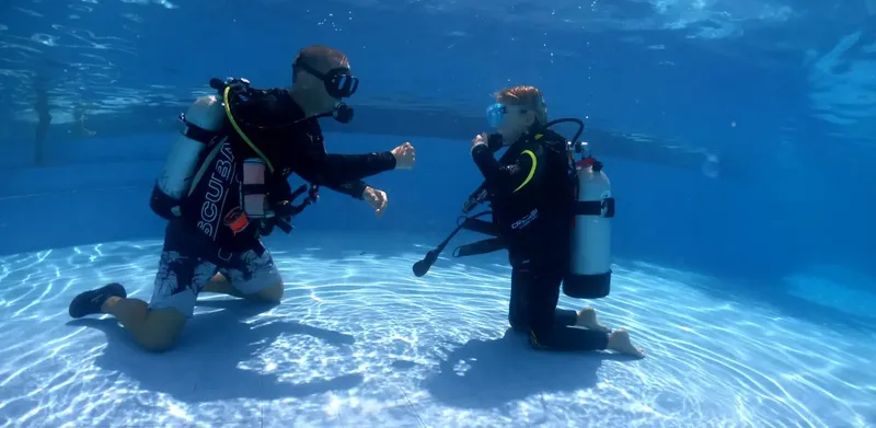 Deux plongeurs s'entraînent en piscine, communication gestuelle sous-marine