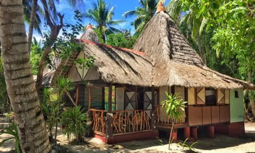 Petites cabanes de plage traditionnelles avec toits de chaume et végétation tropicale