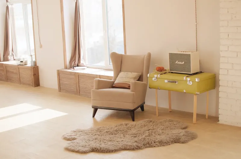 Intérieur lumineux avec fauteuil, valise vintage et tapis moelleux