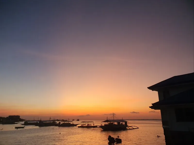 Coucher de soleil sur la mer avec bateaux et bâtiment au bord