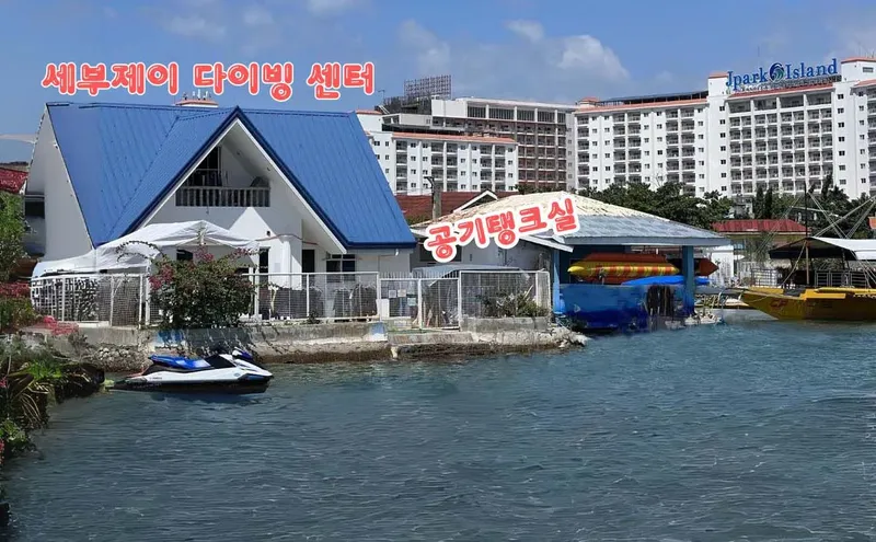 Bâtiment bleu avec texte coréen, jet ski et bateaux amarrés