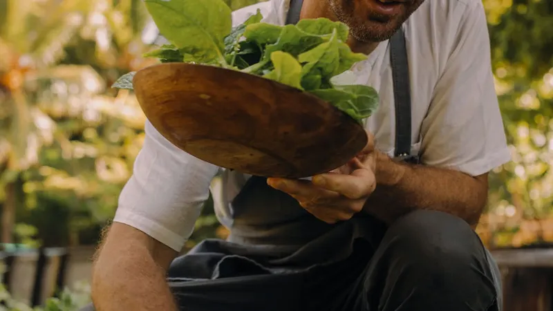 Un homme tient une assiette en bois remplie de feuilles vertes