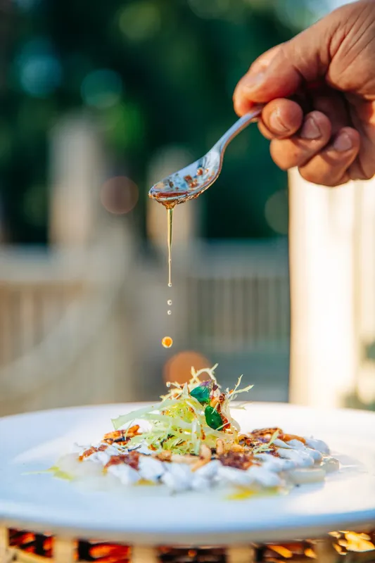 Main versant une sauce sur un plat de nourriture raffinée