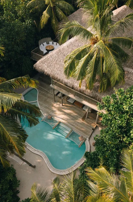 Vue aérienne d'une piscine et d'un bungalow avec toits de chaume