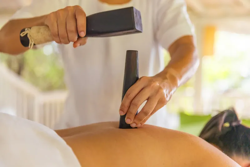 Massage thérapeutique du dos avec des outils en pierre sombre